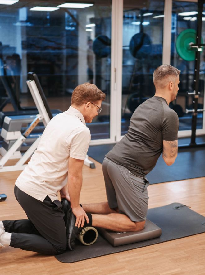 Physiotherapeut unterstützt Mann beim Krafttraining