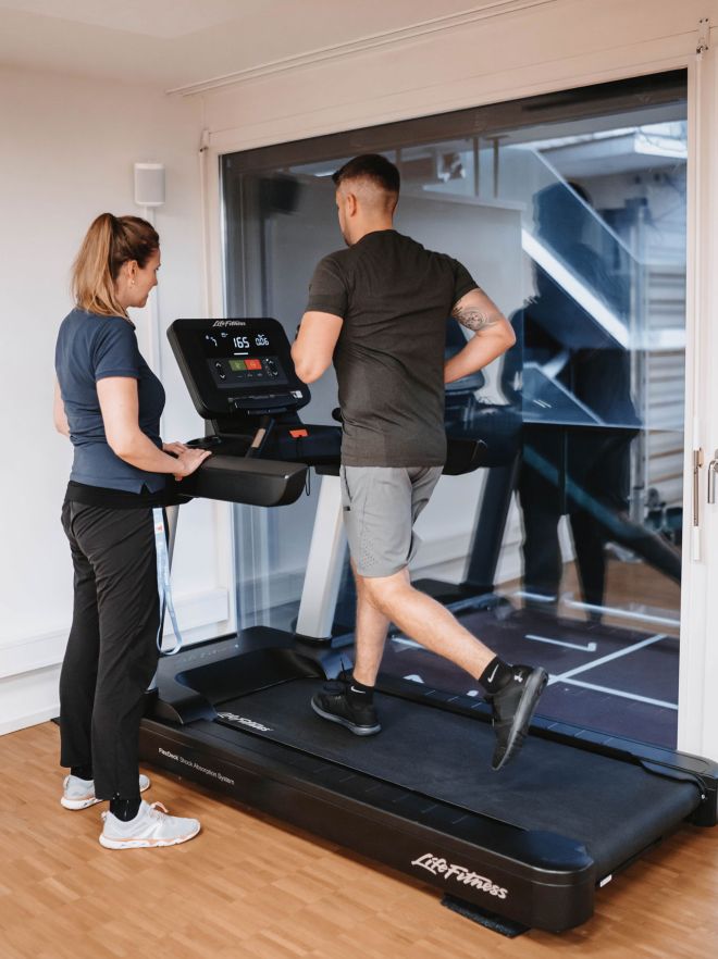 Physiotherapeutin unterstützt Mann beim Lauftraining