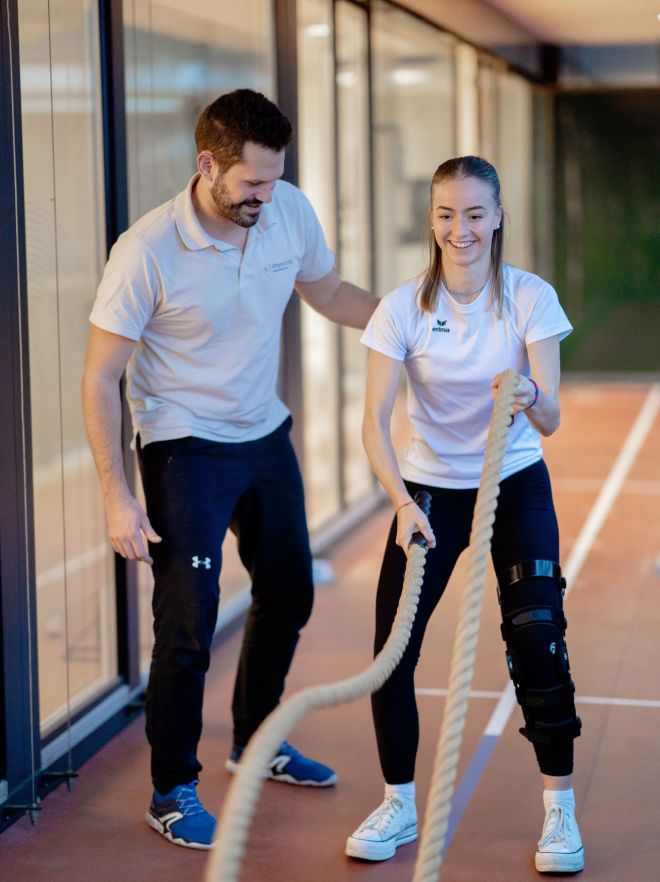 Physiotherapeut trainiert mit junger Frau das Seiltraining